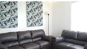 A living room with two dark brown leather sofas, a floor lamp, and two large patterned wall hangings.