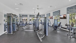 Ein modernes Fitnessstudio mit unterschiedlichen Trainingsgeräten, großen Fenstern und einem hellen, geräumigen Design.