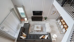 Ein modernes Wohnzimmer mit einem Ecksofa, einem Flachbildfernseher, einem Couchtisch und einem Essbereich mit Tisch und Stühlen.