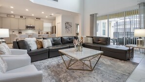 Ein geräumiges Wohnzimmer mit einem Ecksofa, einem Couchtisch und Blick auf die Küche und den Essbereich.
