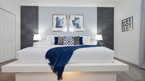 Ein modernes Schlafzimmer mit einem großen Bett, zwei Wandleuchten und zwei gerahmten Kunstwerken darüber.