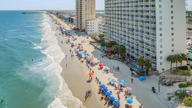 A beachfront hotel with multiple balconies, a pool area, and a beach with umbrellas. - Breathtaking Views Oceanfront 2 Bed 2 Bath Condo Water's Edge Resort Garden City (Murrells Inlet)