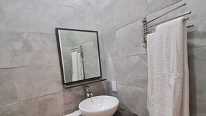 A modern bathroom with a white sink, dark vanity, a mirror, and a towel rack. - Yamabeach Stays (Nassau)