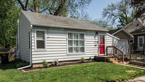 Une maison de plain-pied avec un porche à l’avant, un petit jardin devant et une porte de garage bien visible.