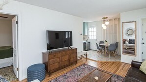 Un salon moderne doté d’un téléviseur à écran plat, d’un meuble en bois et d’un coin repas avec des chaises et une table.