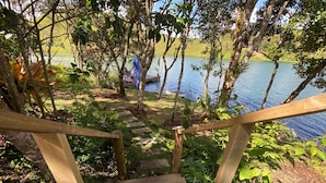 A wooden staircase leading to a lakeside area with a boat docked in the background. - Celeste Glamping Guatape (Guatapé)