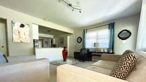 A living room with a sofa, armchair, and a dining area with a table and chairs.
