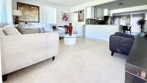 A modern living room with a sofa, a coffee table, and a dining area with a table and chairs.