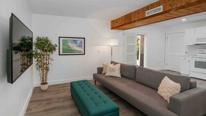 A living room with a grey sofa, teal ottoman, and a potted plant. - [escape to paradise] siesta key beach getaway (Siesta Key)