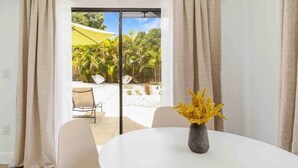 A room with a round white table, a vase with yellow flowers, and a view of a garden through a sliding glass door. - [escape to paradise] siesta key beach getaway (Siesta Key)