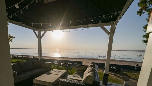 Un área de estar al aire libre y cubierta con vista a la playa y el océano.