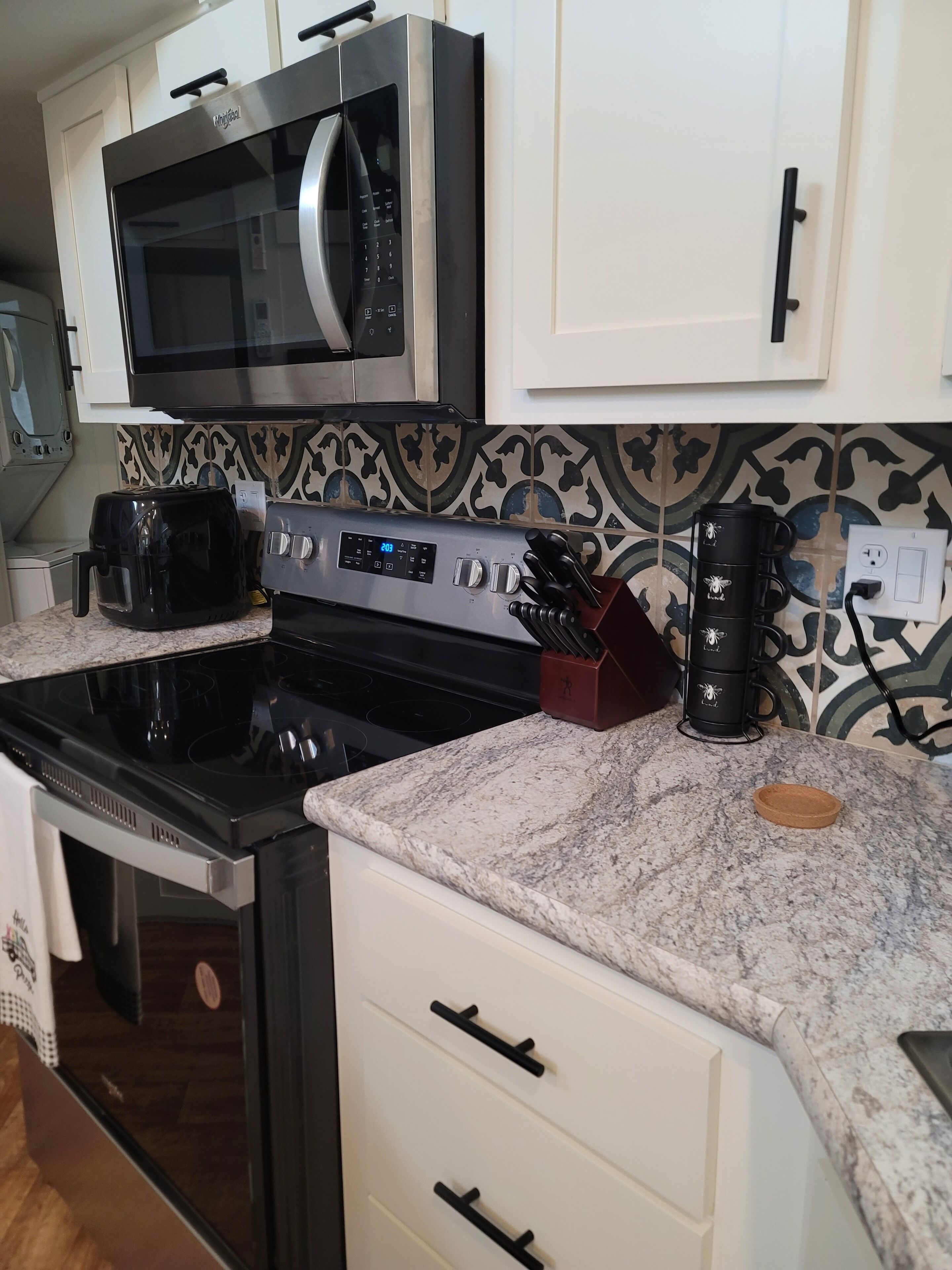 Uma cozinha moderna com micro-ondas de aço inoxidável, forno embutido, cafeteira e torradeira.