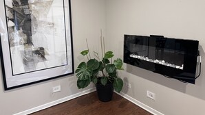 A framed abstract painting, a potted plant, and a black fish tank with rocks on a white wall. - Entire Residential home (Darien)