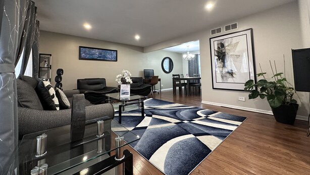 A modern living room with a sofa, coffee table, and rug. There is a dining area with a table and chairs. - Entire Residential home (Darien)