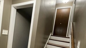 A staircase with wooden steps and white railings, leading to a door with a light fixture above it. - Entire Residential home (Darien)