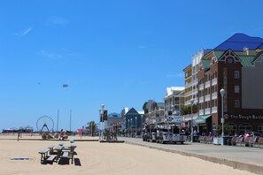 A beachside boardwalk with benches, a Ferris wheel, and buildings with shops. - The Reef Apartments Unit 3&4 - Downtown/5minute walk to beach! (Ocean City)