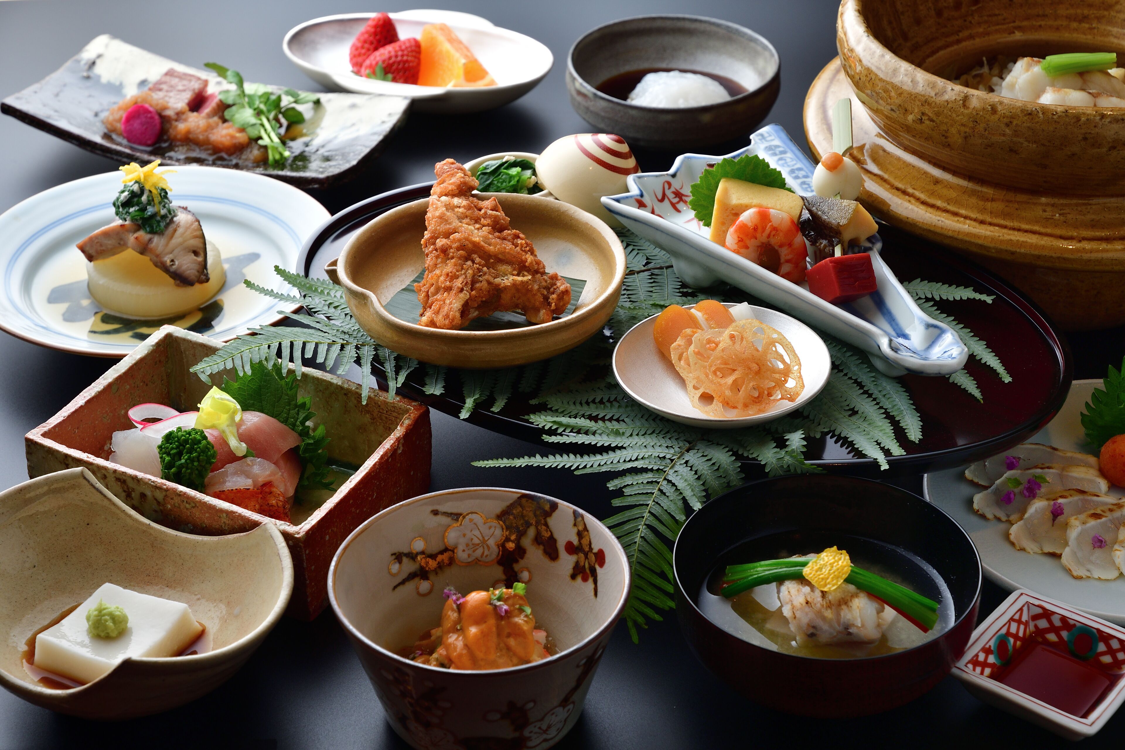 Verschiedene Gerichte auf einem Tisch, darunter Sushi, Sashimi und andere Spezialitäten der asiatischen Küche.