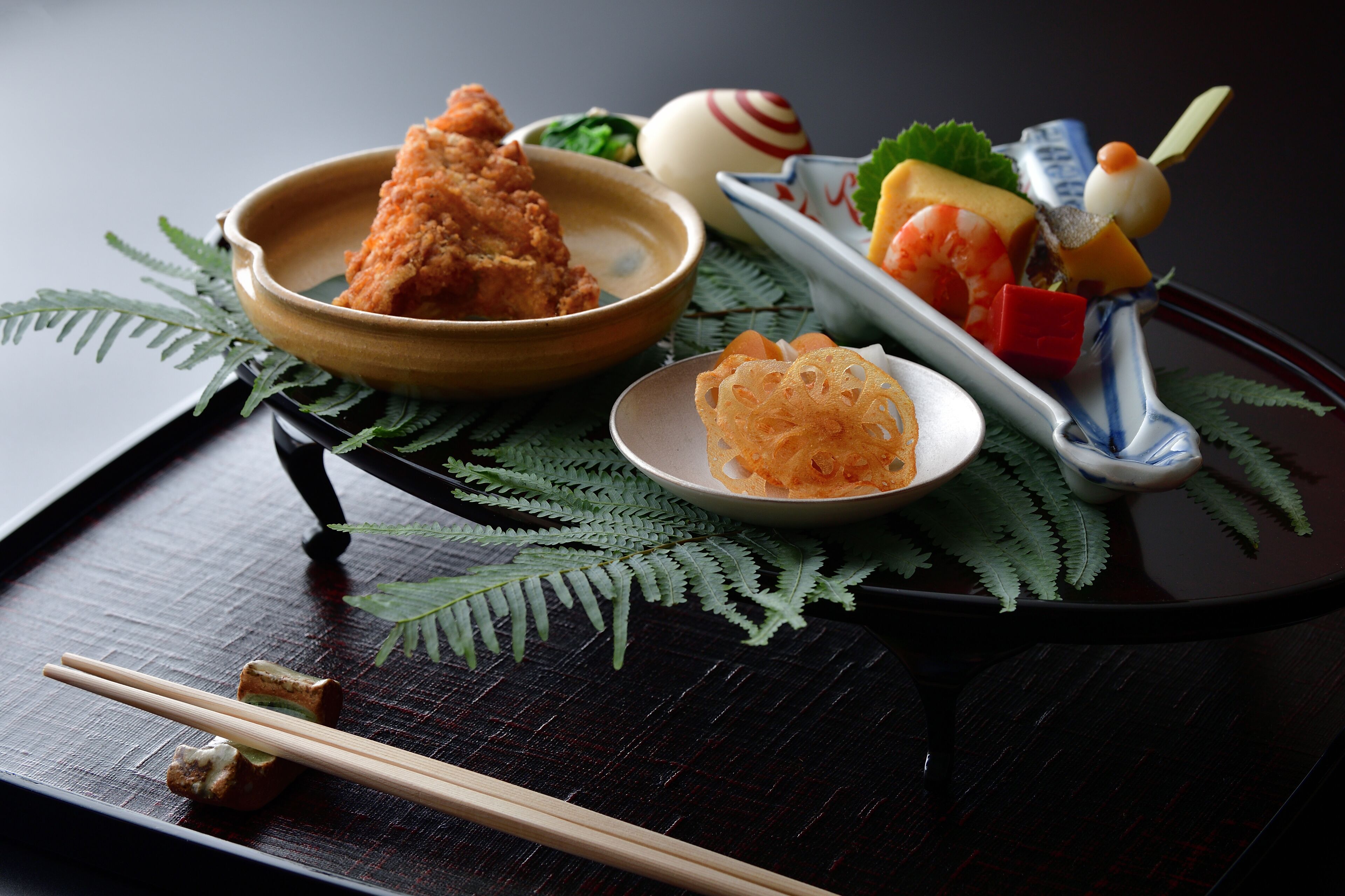 A tray with various Japanese dishes, including tempura, sashimi, and a small bowl of pickled vegetables.