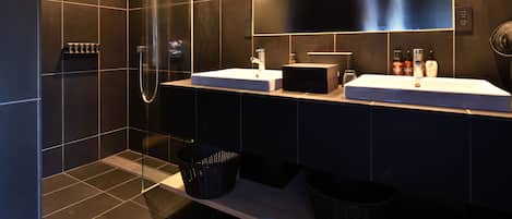 Un baño moderno con dos lavamanos, un espejo grande y una zona de ducha.