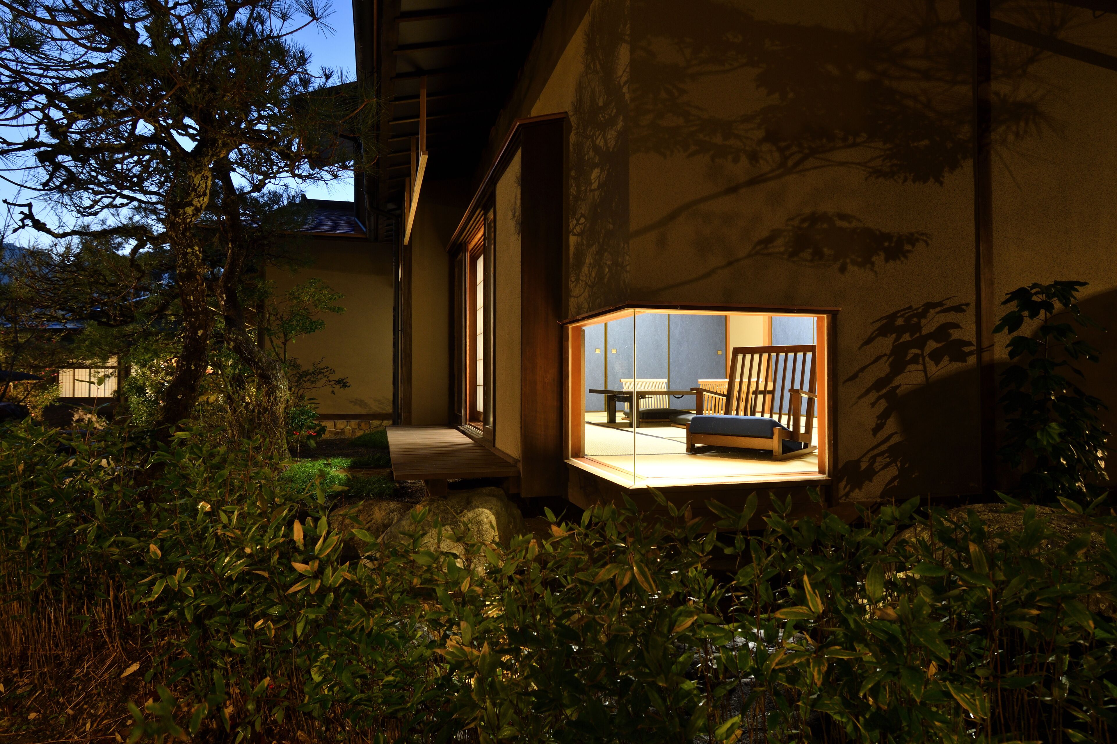 A traditional Japanese-style building with a wooden exterior and a glass window revealing a room with tatami mats and a low table.