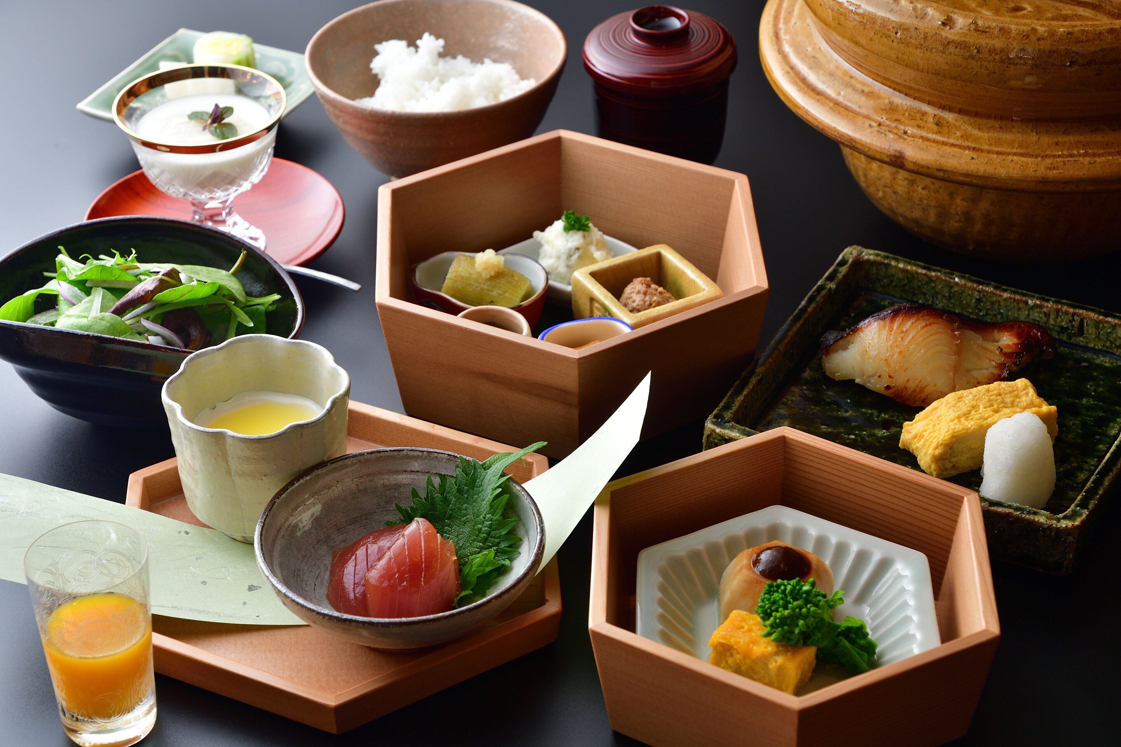 A variety of traditional Japanese dishes arranged on a table, including sushi, rice, and pickled vegetables.