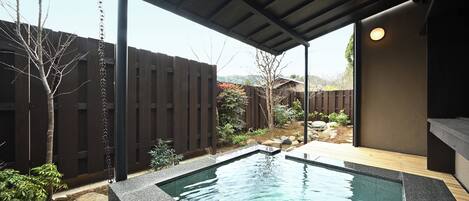 A backyard with a swimming pool, wooden deck, and a covered patio area.