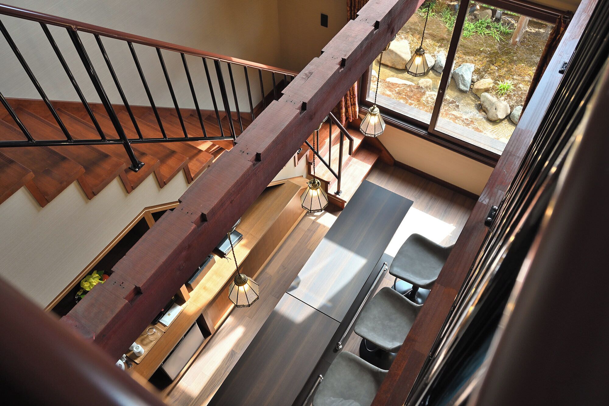 A wooden staircase with a metal railing, a bench, and a view of a garden through a window.