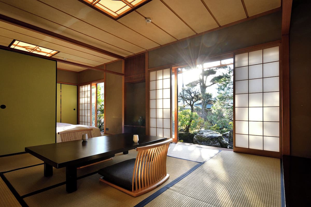 A traditional Japanese room with tatami flooring, a low table, and sliding doors.