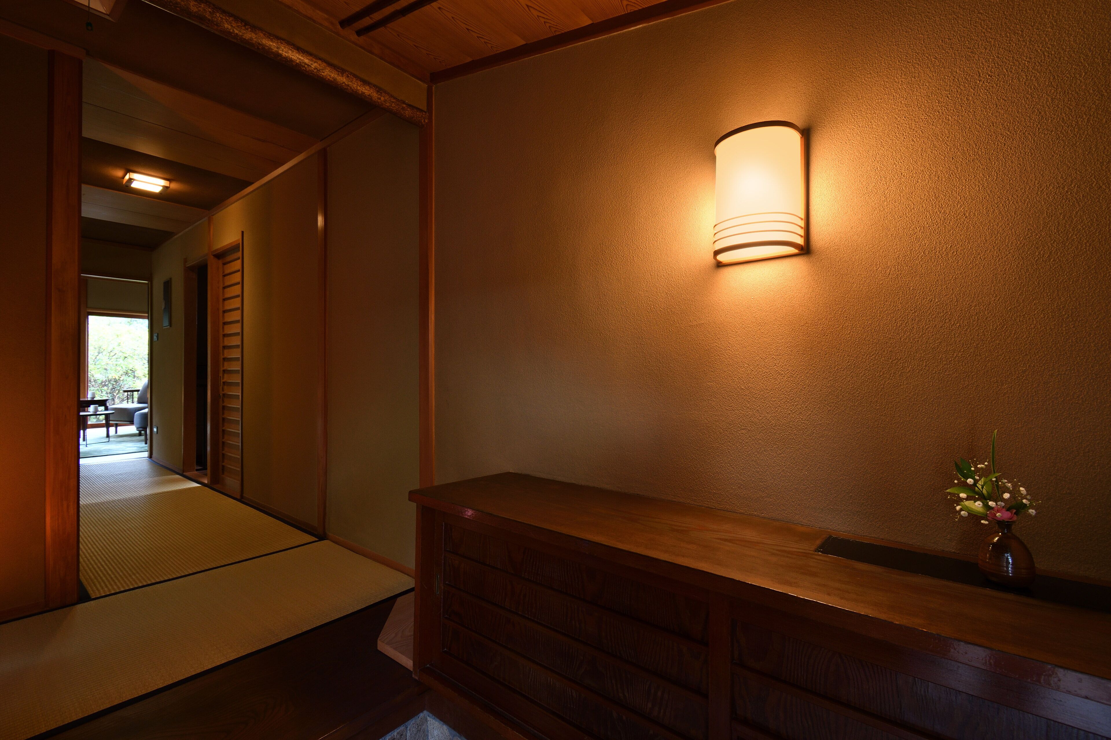Et traditionelt japansk interiør med tatamigulv, en træreception og en vægmonteret lampe.