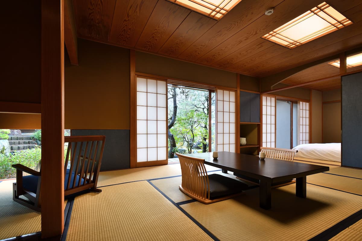 A traditional Japanese-style room with tatami flooring, a low table, a cushioned chair, and sliding doors.