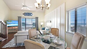 A dining area with a glass table, chairs, and a view of the ocean. - Gulf Front PCB Condo, Stunning Views, Pool, Balcony, Sleeps 6 (Panama City Beach)