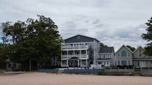 Ein großes, mehrgeschossiges Gebäude mit einem markanten Balkon, in der Nähe eines Sandstrandes und eines Gewässers gelegen.