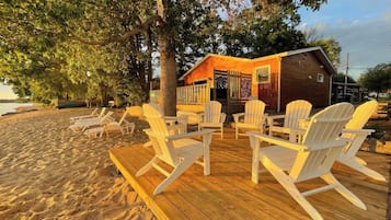 A wooden deck with Adirondack chairs and a small cabin with a wooden exterior.