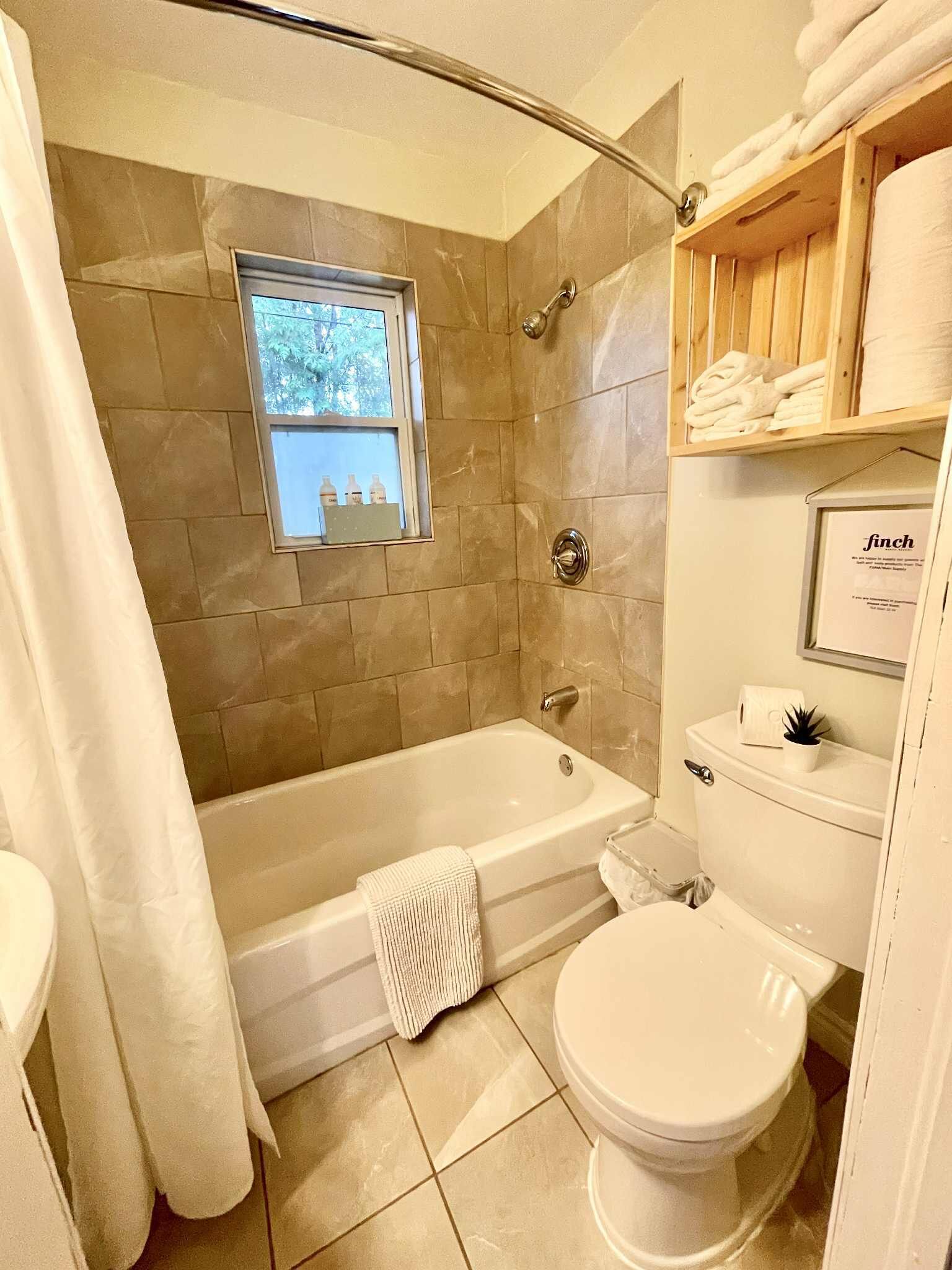 A bathroom with a bathtub, toilet, and a window.