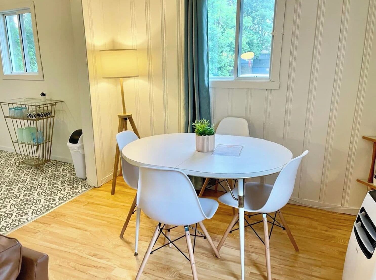 A round table with white chairs, a small potted plant, and a lamp.