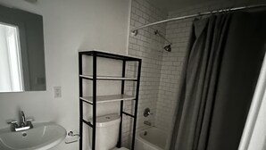 Ein kleines Badezimmer mit einem Standwaschbecken, einer Toilette und einer Badewanne.