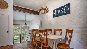 Un comedor con pared de ladrillo blanco, un letrero con la palabra 'LAKE' y una araña.
