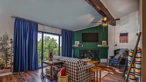 Una sala de estar acogedora con un sofá grande, una chimenea y un televisor montado en la pared.