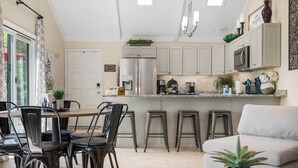A modern kitchen with a central island, bar stools, and a dining area with chairs. - Lakefront House w/ Private Dock in a Protected Cove -Swim, Kayak, Fish!  MM20 (Osage Beach)