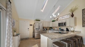 A modern kitchen with a central island, bar stools, and a chandelier. - Lakefront House w/ Private Dock in a Protected Cove -Swim, Kayak, Fish!  MM20 (Osage Beach)