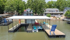 A docked house with a covered deck, a small boat, and a kayak. - Lakefront House w/ Private Dock in a Protected Cove -Swim, Kayak, Fish!  MM20 (Osage Beach)