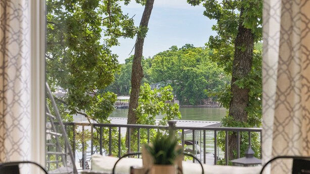 A dining area with a view of a lake and trees. - Lakefront House w/ Private Dock in a Protected Cove -Swim, Kayak, Fish!  MM20 (Osage Beach)