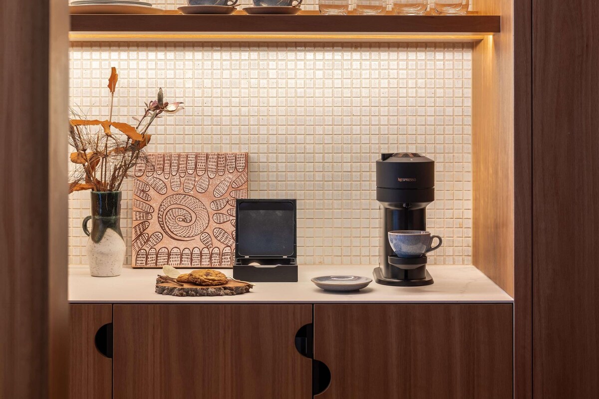 Eine Küche mit Kaffeemaschine, einer Vase mit Trockenblumen und einer dekorativen Fliesenrückwand.