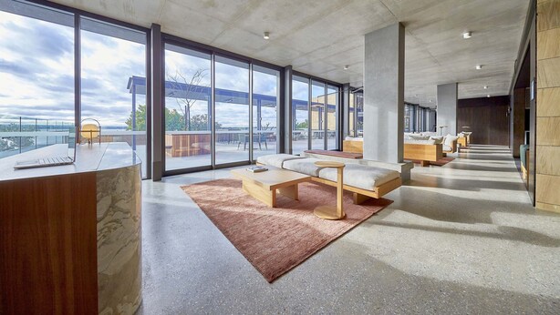 Un moderno vestíbulo de hotel con amplias ventanas, una recepción, zonas de estar y vistas al exterior.