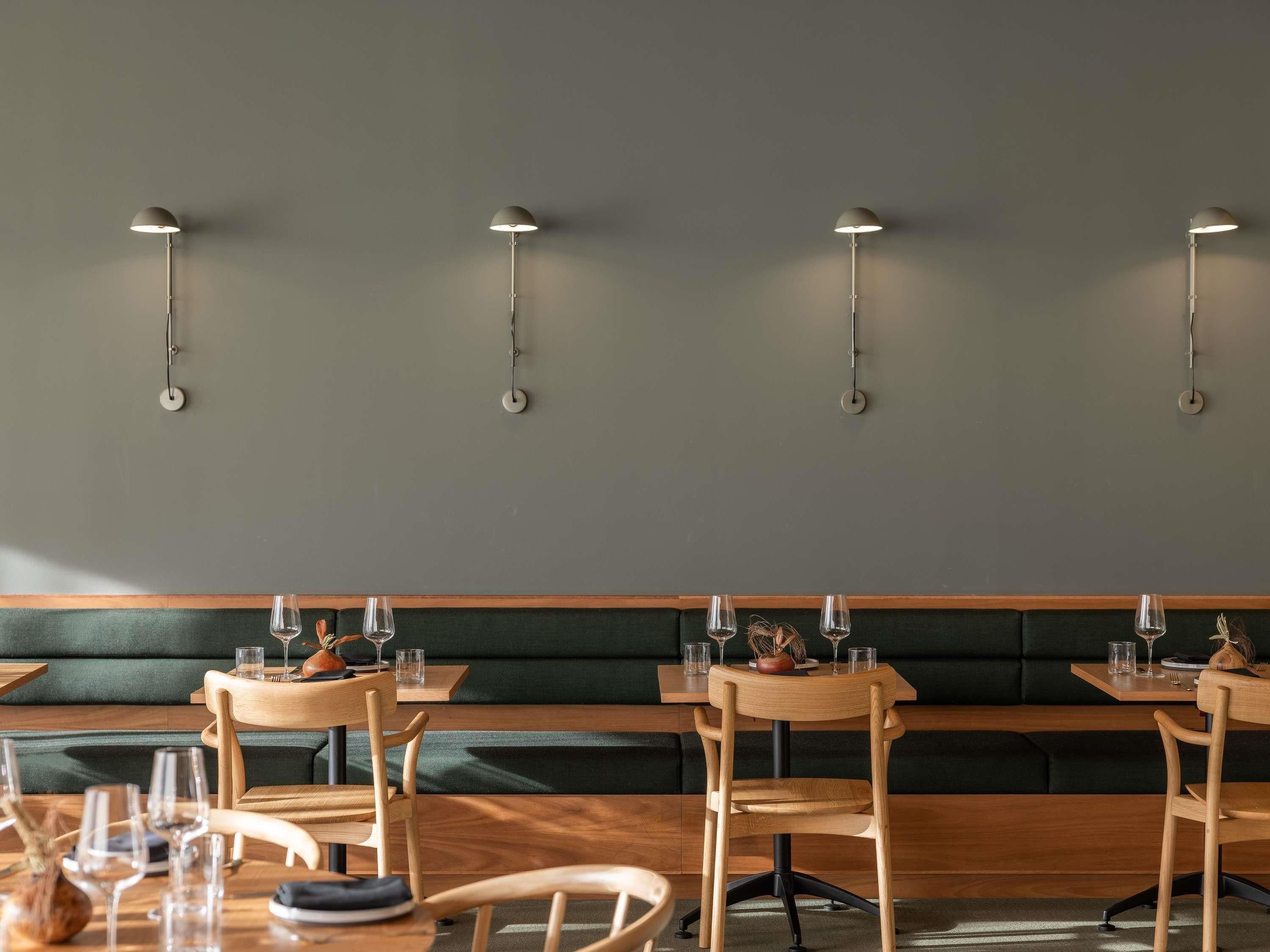 A restaurant interior with wooden tables, chairs, and a green cushioned bench.