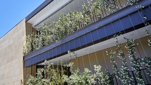 A modern building facade with a series of balconies adorned with flowering plants. - Wonil Hotel Perth - Handwritten Collection (Crawley)