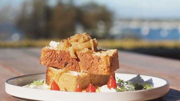 A plate with a sandwich on a wooden table outdoors.