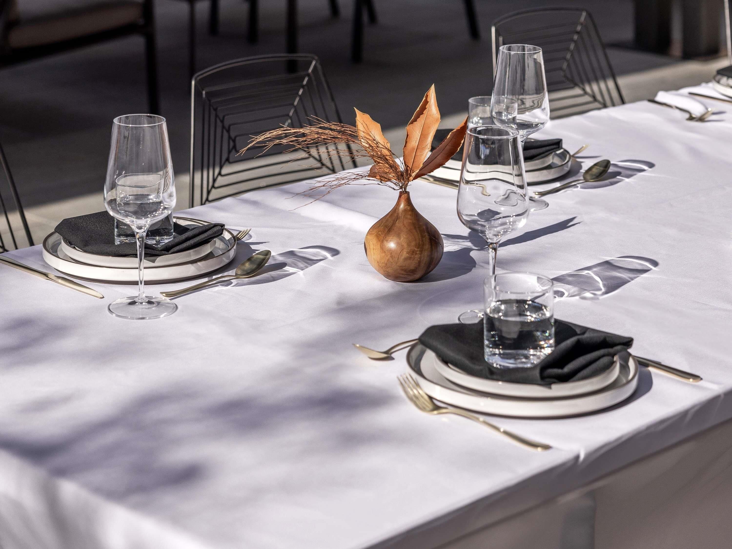 Una mesa cubierta con manteles blancos, servilletas negras y cubiertos.