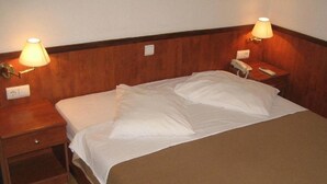 A hotel room with a bed, two bedside tables, lamps, a phone, and a nightstand. - Aurora Hotel (Podgora)