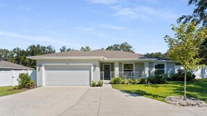 Una casa a un piano con garage, portico anteriore e prato curato.